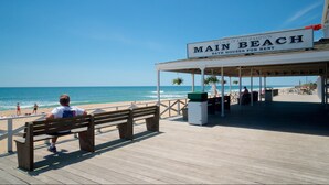 A wooden pier with a covered seating area labeled "Main Beach" and a sign indicating "Village of East Hampton Bath Houses for Rent." - East Hampton Luxury: Heated Pool, Hot Tub and Expansive Yard with 6 Bedrooms (East Hampton)