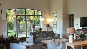 A spacious living room with a large window, a sofa set, a coffee table, and a television.