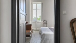 Un pasillo estrecho que conduce a un dormitorio con una cama, un escritorio pequeño y una silla.