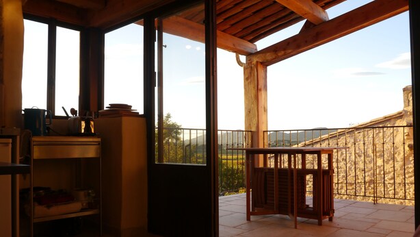 Ein Zimmer mit Holzboden, einer Schiebetür zum Balkon und einem kleinen Tisch mit Stühlen.