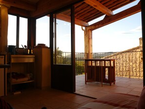 A room with a wooden ceiling, a sliding glass door leading to a balcony, and a small table with chairs. - Manescau house, near Mont Ventoux, near Bedoin (Saint-Pierre-De-Vassols)