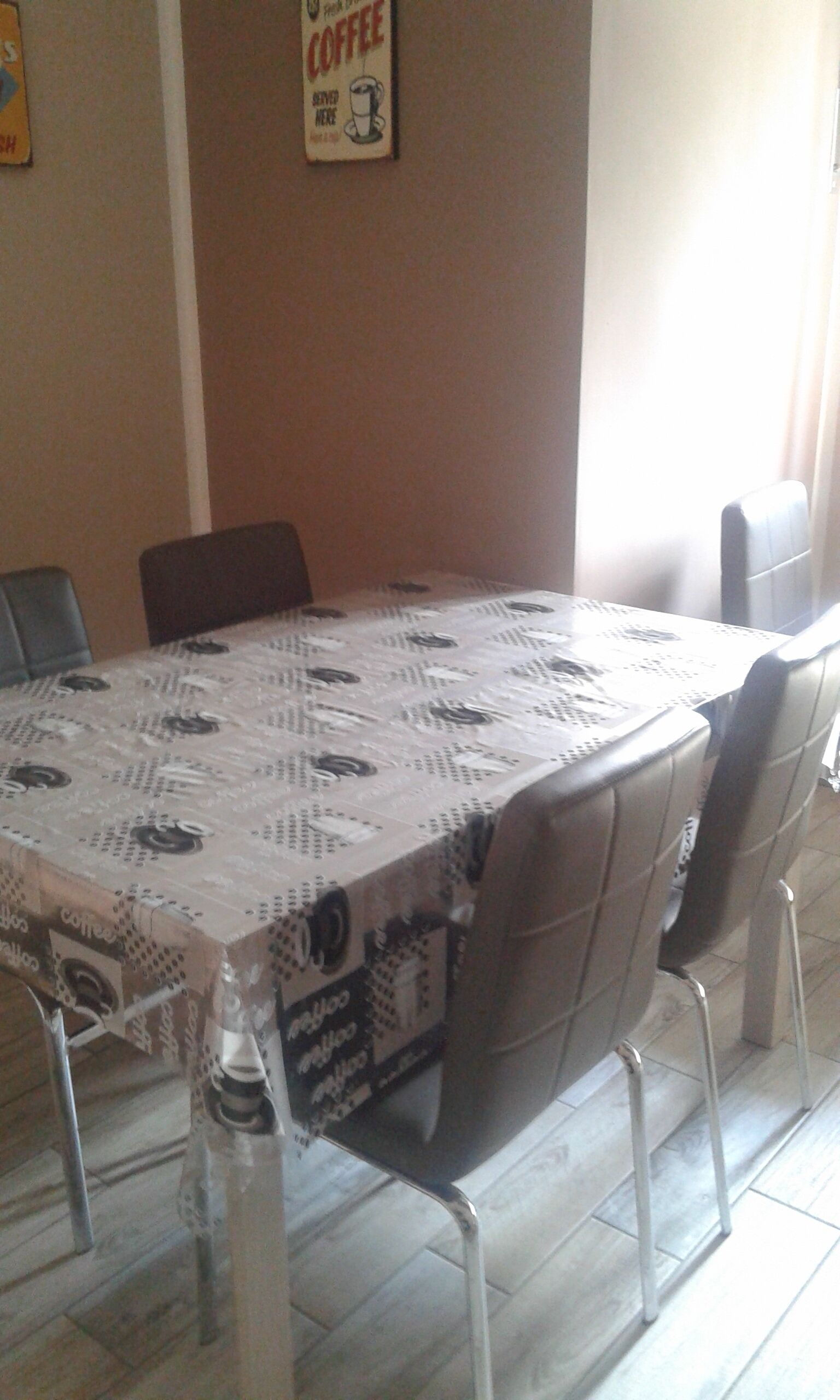 Un tavolo da pranzo con una tovaglia a tema caffè, circondato da sedie.