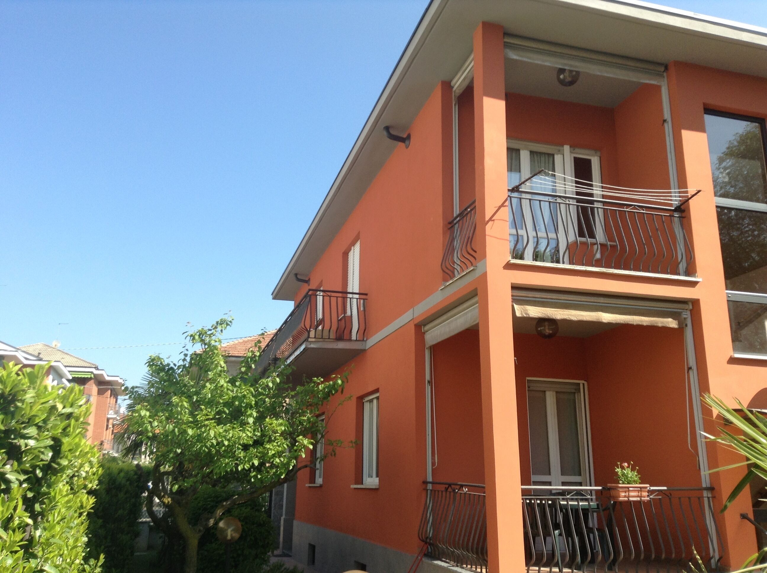 A multi-story building with balconies, a visible door, and a window with a curtain.