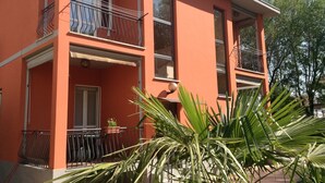 A two-story building with balconies, large windows, and a red facade.
