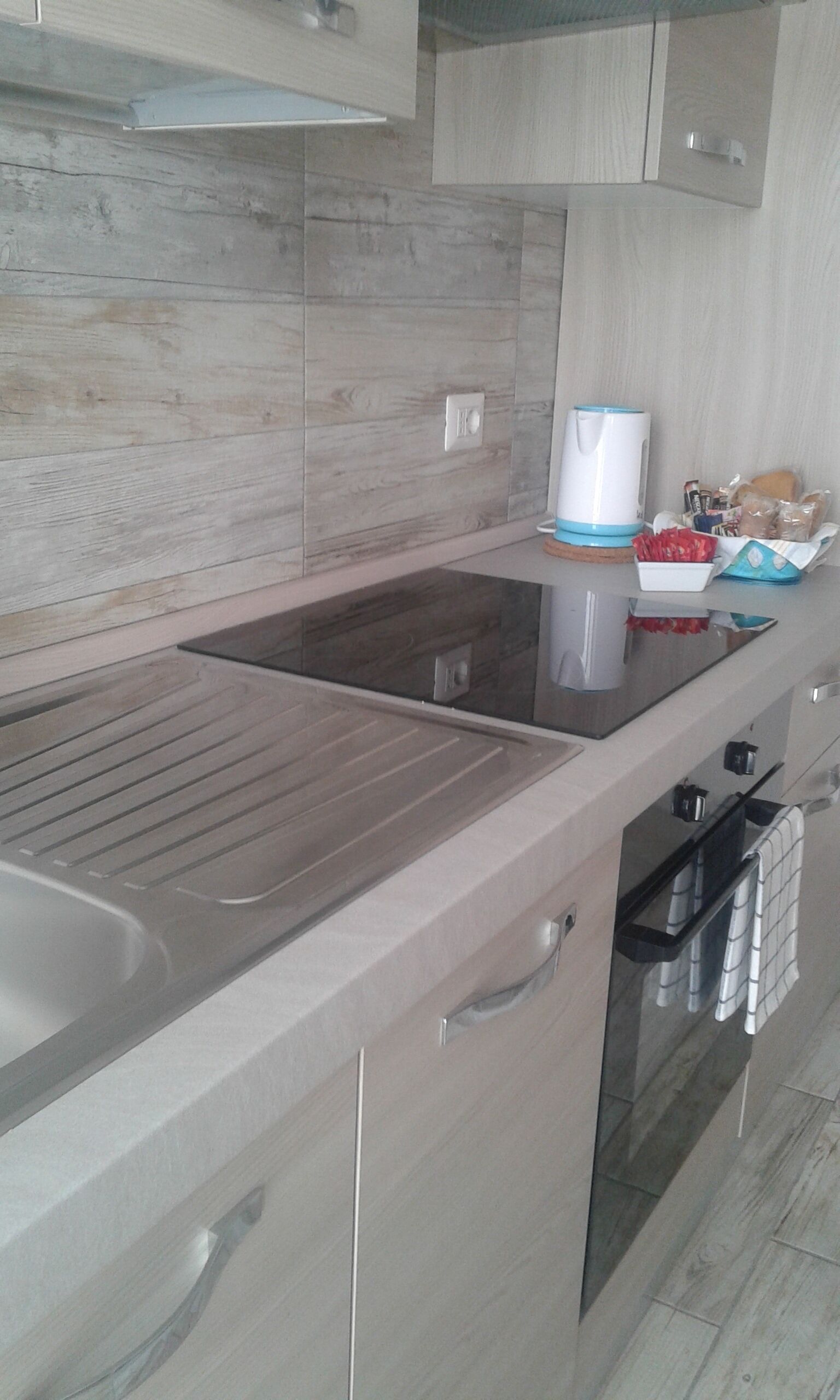 A modern kitchen with a stainless steel countertop, a built-in oven, and a microwave.