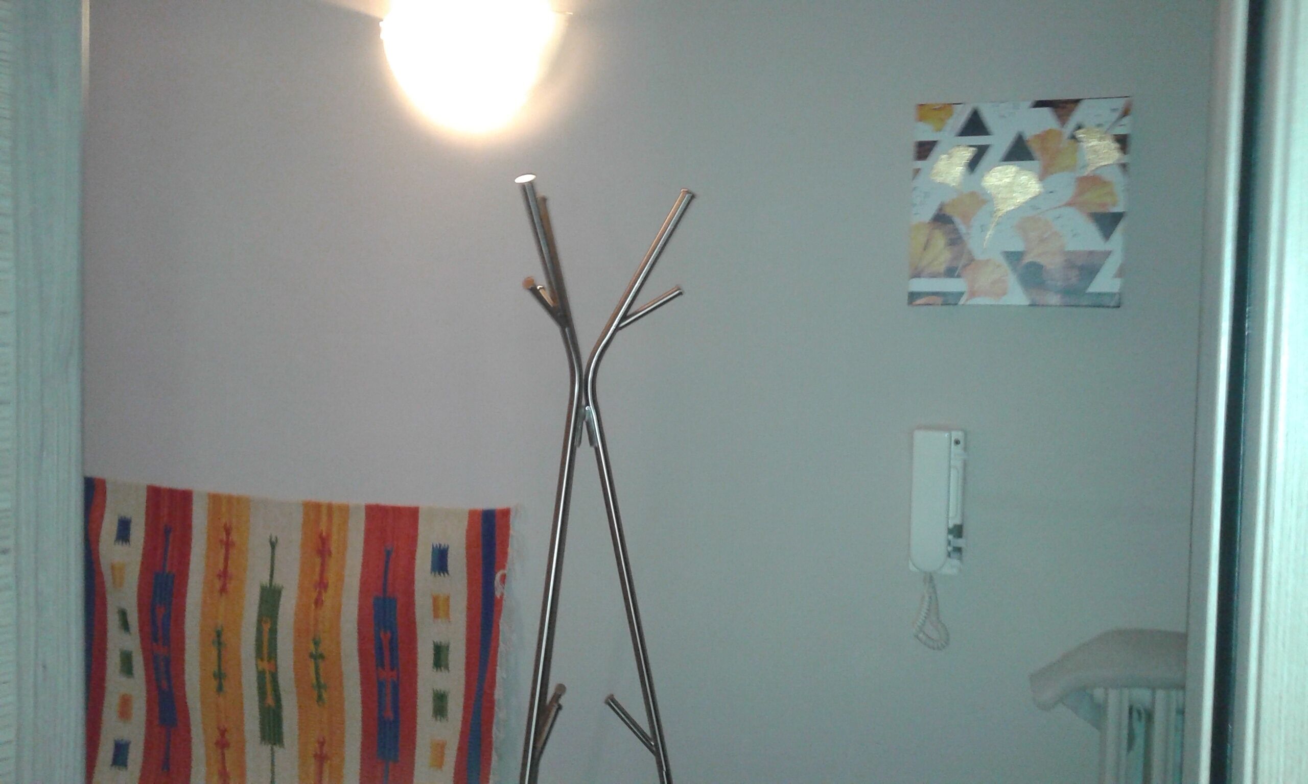 Una habitación con una escultura de madera, un cuadro abstracto colorido y una obra de arte geométrica en la pared.