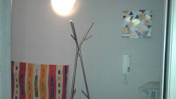 Una habitación con una escultura de madera, un cuadro abstracto colorido y una obra de arte geométrica en la pared.