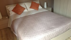 A neatly made bed with a quilted cover and two decorative pillows.