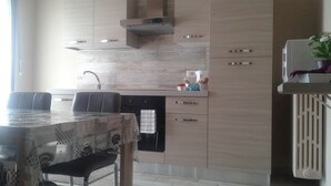 A modern kitchen with a built-in stove, a sink, and a dining area with a table and chairs.