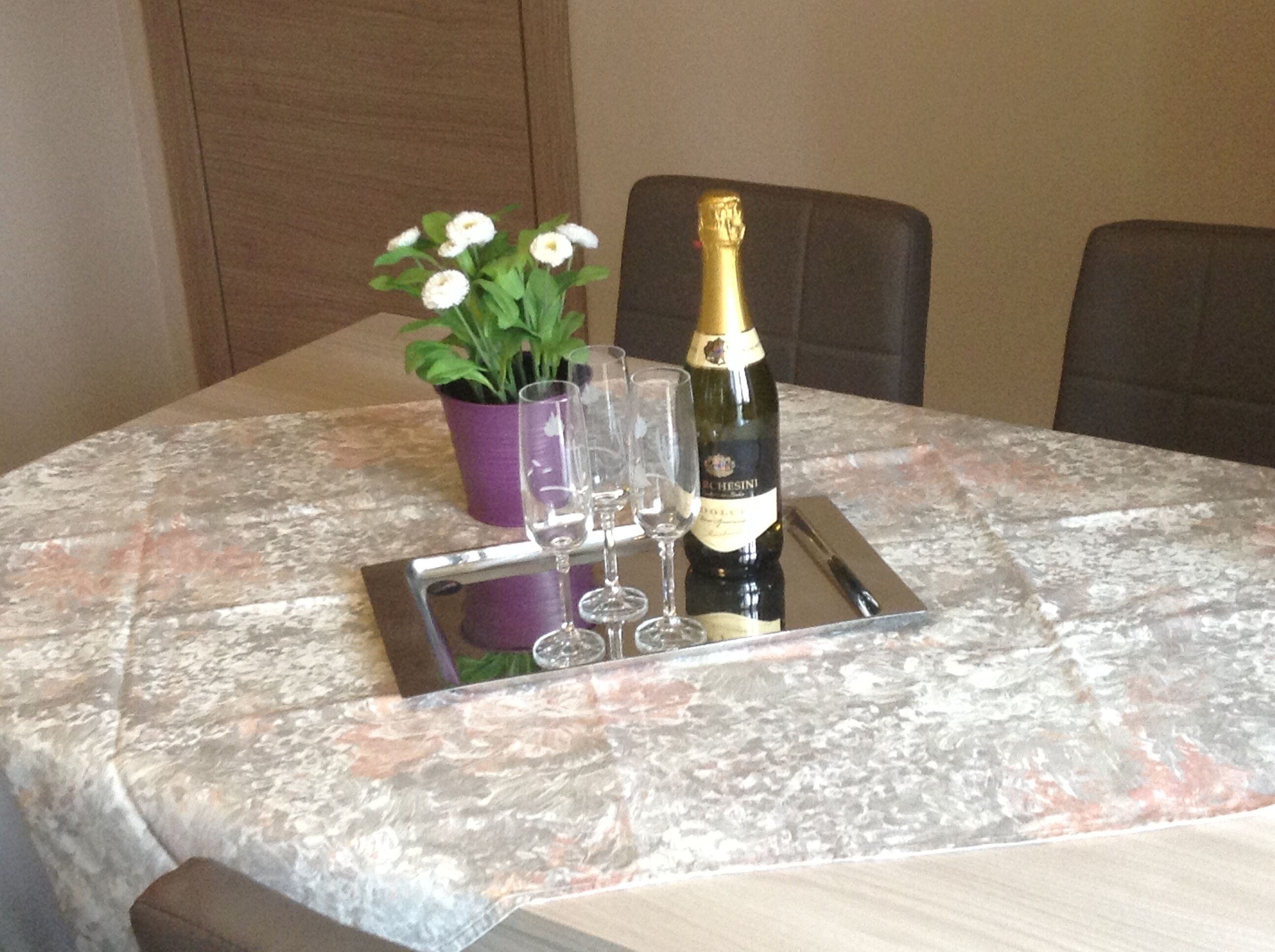 Une table dressée avec une bouteille de champagne, des verres et une petite plante en pot.