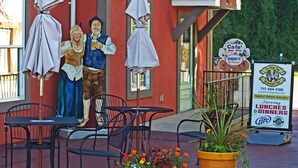 A cafe with outdoor seating, a mural of two figures, and a sign advertising lunch and dinner services.