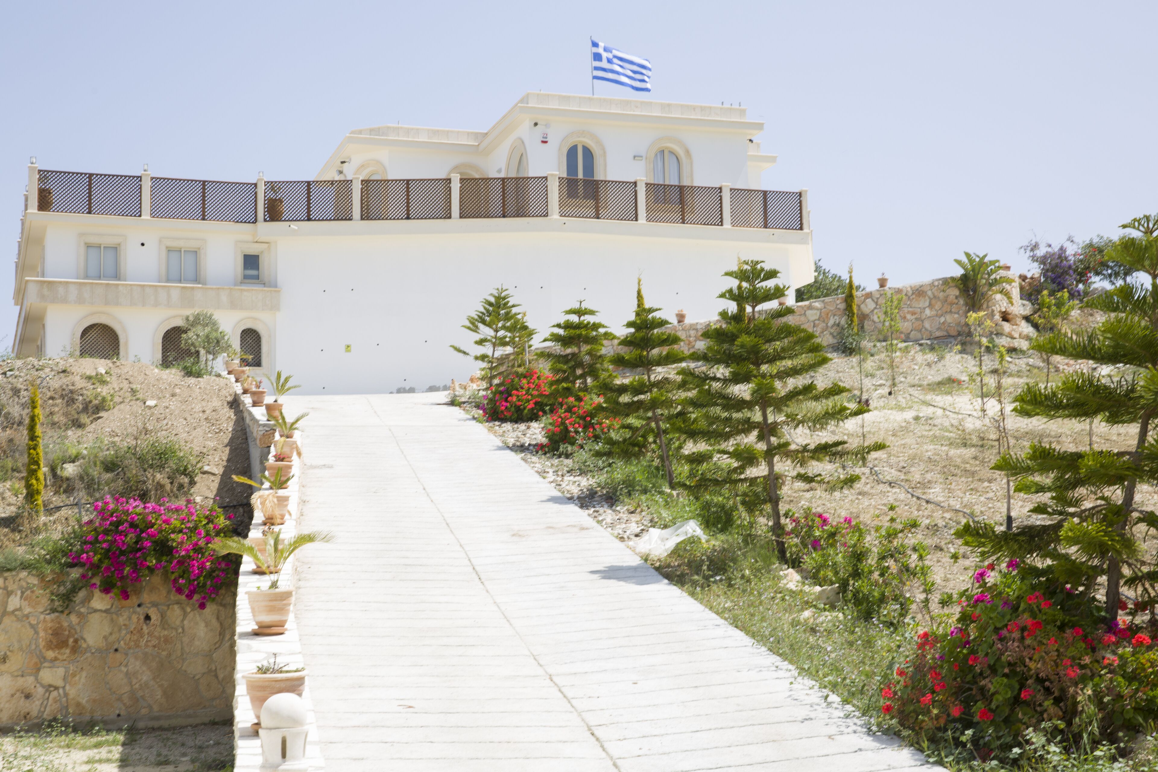 A building with a white facade, a balcony with a railing, and a flag on top.
