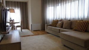 Una sala de estar con sofá, mesa de centro, televisor y un comedor con sillas y mesa.