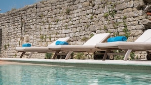 Ein Poolbereich mit Steinmauern und Liegestühlen.