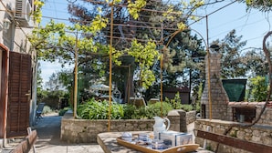 Eine Terrasse mit Esstisch, umgeben von Steinmauern und Grünpflanzen.