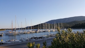 Ein Yachthafen mit mehreren Segelbooten, ein klarer Himmel und eine gebirgige Kulisse.