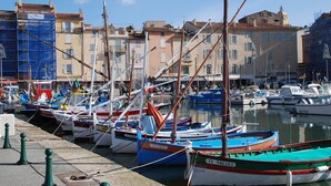 Un puerto deportivo con barcos amarrados a lo largo de la costa, edificios al fondo y un cielo despejado.