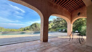 Un espacio al aire libre cubierto con piscina, sillas de descanso y una mesa.