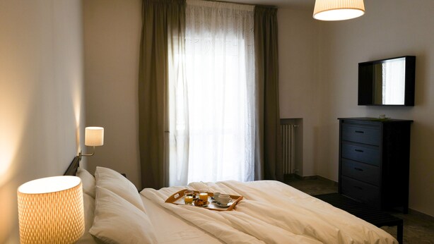 A hotel room with a bed, a bedside lamp, a tray with breakfast items, a dresser, and a mirror on the wall. - Large apartment in the center of Lecce (Lecce)