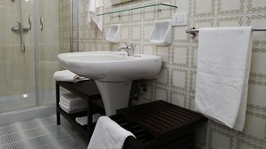 A bathroom with a glass shower enclosure, a white sink, and a mirror above it. - Large apartment in the center of Lecce (Lecce)