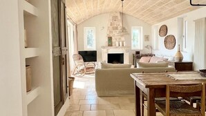 Amplia sala de estar con chimenea, suelo de piedra y un alto techo con vigas a la vista.