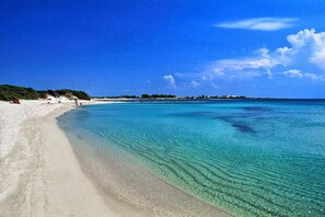 A beach with clear turquoise water, white sand, and a distant shoreline with buildings. - "Casa Bova Mary" central Mesagne (Mesagne)