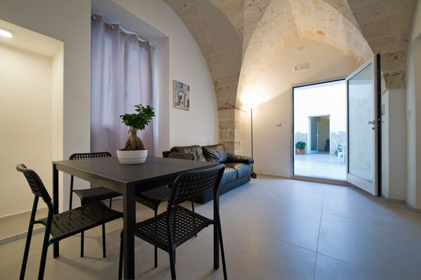 A dining area with a table and chairs, a potted plant, a sofa, and a sliding glass door leading to an outdoor space. - "Casa Bova Mary" central Mesagne (Mesagne)
