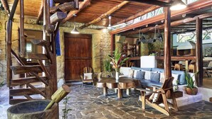 Un interior rústico con suelo de piedra, mobiliario de madera y pared de piedra.