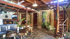 Un interior rústico con suelo de piedra, muebles de madera y una escalera.