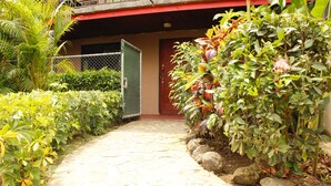 A stone pathway leading to a building with a red door.