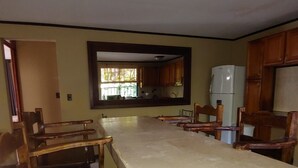 A kitchen with a marble countertop, wooden chairs, and cabinets.