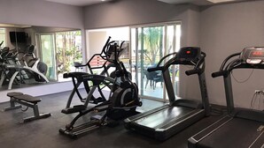 Ein Fitnessraum mit Laufbändern, Crosstrainern und einer Bank.