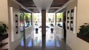 Ein moderner Hotelkorridor mit poliertem Boden, Zimmerpflanzen und gerahmten Kunstwerken an den Wänden.