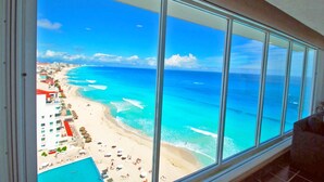 A panoramic view of a beach resort with a large window overlooking the ocean and beach. - The Most Amazing Views! Beachfront Penthouse 3BR3/Bth (Cancun)