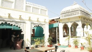 A traditional building with ornate white walls and arches, a small dome, and potted plants. - Venus Heritage in the family  (Udaipur)