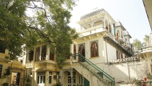 A traditional building with a staircase leading to a balcony, surrounded by potted plants. - Venus Heritage in the family  (Udaipur)