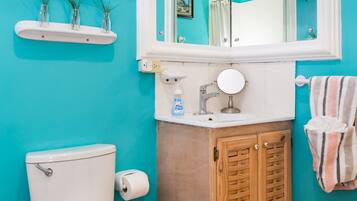 A bathroom with a white toilet, a sink with a mirror, a wooden cabinet, and a blue wall.