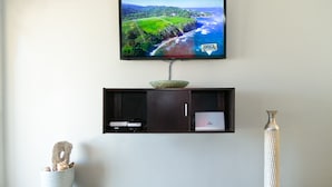 Ein Flachbildfernseher ist an einer Wand über einem dunklen Holzschrank angebracht, auf dessen Oberseite sich eine dekorative Schale befindet.