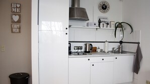 A kitchen with white cabinets, a stainless steel range hood, a clock, and a plant. - ELBQUARTIER | Charming apartment with elevator right in the center (Wedel)