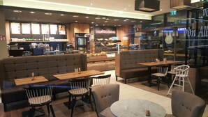 A cozy café with seating areas, a coffee bar, and a bakery display. - ELBQUARTIER | Charming apartment with elevator right in the center (Wedel)