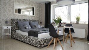 A bedroom with a bed, bedside table, chair, and a window with plants. - ELBQUARTIER | Charming apartment with elevator right in the center (Wedel)