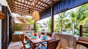 A wooden dining table set with plates, bowls, and a fruit bowl, surrounded by wicker chairs with patterned cushions. - BEAUTIFUL CONDO AT THE PACIFIC COAST IN AN EXCLUSIVE LOCATION (El Gariton)