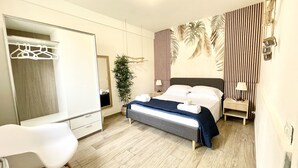 A modern hotel room with a bed, a bedside table, a chair, a mirror, and a wardrobe.