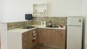 Une cuisine de taille réduite, équipée d’un évier, d’une cuisinière et d’un réfrigérateur blanc.