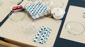 Une table dressée avec des bols en verre transparent, un plateau en métal et une serviette à pois.