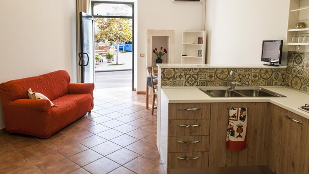 Un espace de vie compact comprenant un coin cuisine, un canapé, un coin repas et une vue sur l’extérieur.