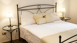 Un lit bien fait, avec du linge de lit blanc, deux tables de chevet avec des lampes et une simple tête de lit en métal.