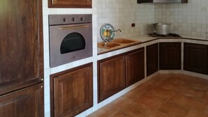 Une cuisine avec des meubles en bois, un four en acier inoxydable, un évier et un dosseret carrelé.