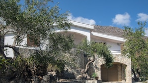 Un bâtiment en pierre avec une façade blanche, une porte en bois et un escalier en pierre menant à l’entrée.