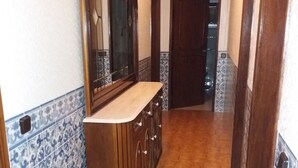Ein Flur mit Holzschrank und Spiegel, mit Fliesenwänden und -boden.